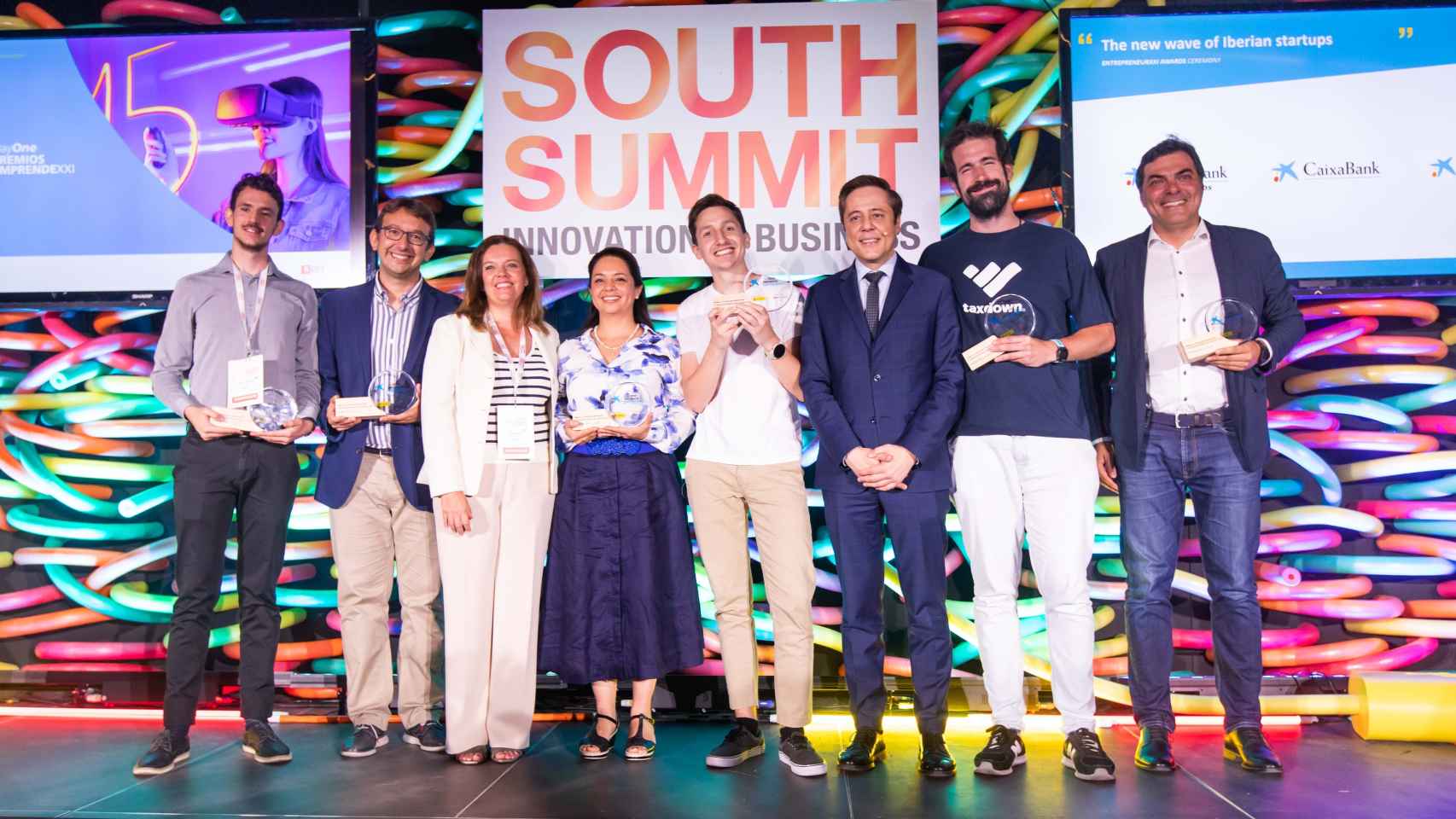 Los representantes de las startups galardonadas posan con miembros de la organización de los Premios EmprendeXXI tras la entrega de las distinciones en el escenario del South Summit 2022.