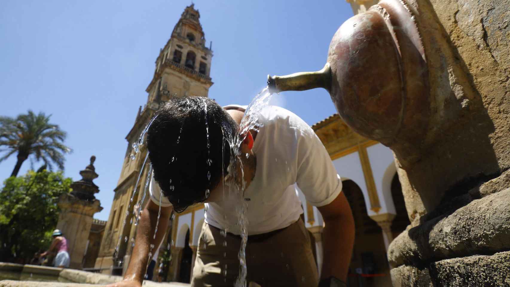 Un turista se refresca este domingo en una de las fuentes del Patio de los Naranjos de la Mezquita catedral de Córdoba para aliviar las altas temperaturas. Foto: EFE/Salas