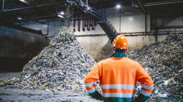 Un trabajador de una planta de reciclaje observando el proceso de gestión de residuos.