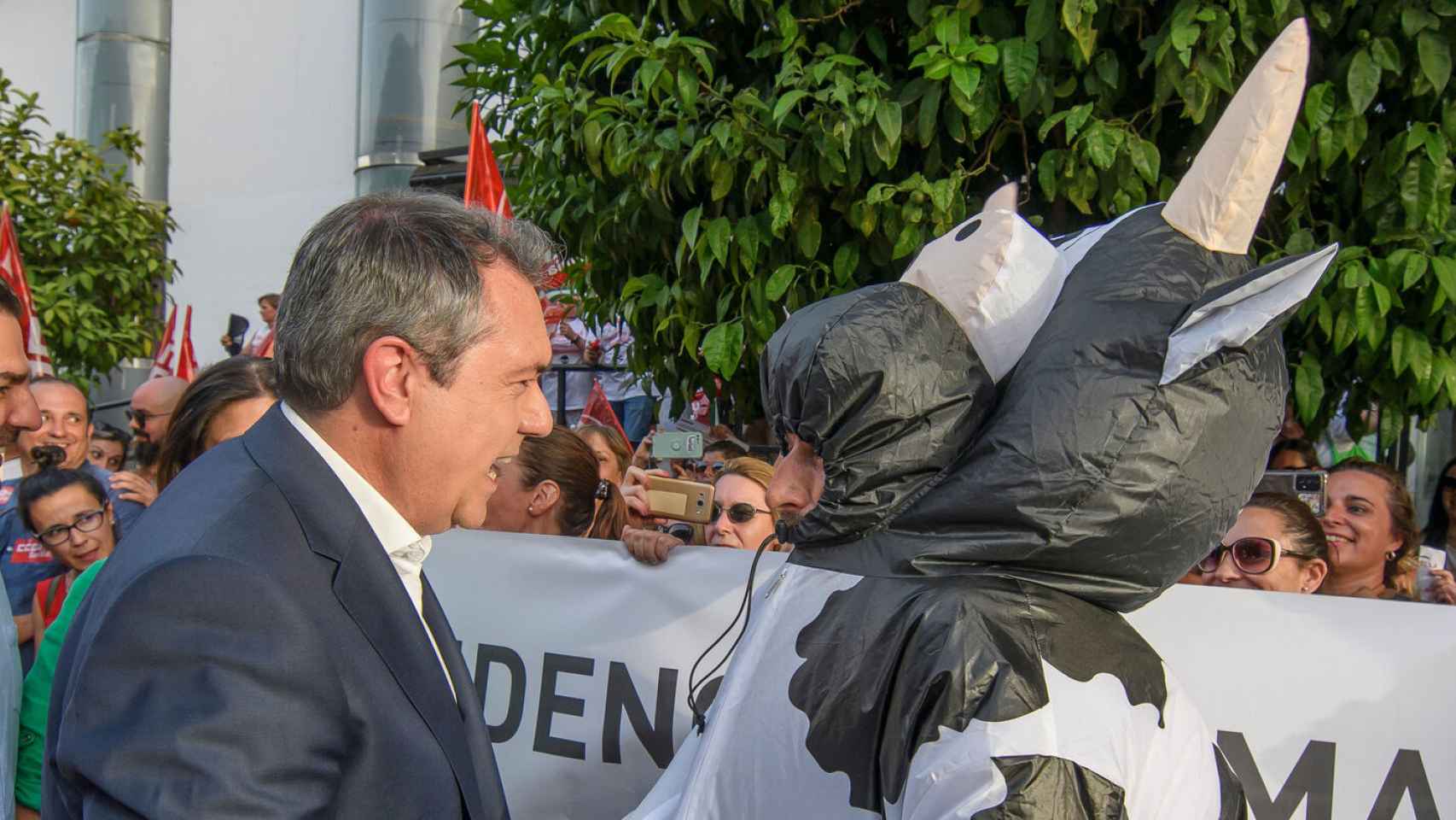 El candidato del PSOE, Juan Espadas, saluda a un manifestante disfrazado de 'Fadie'.
