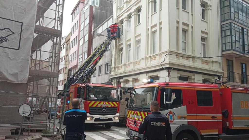 Los bomberos limpian la fachada de un edificio afectada por la explosión de una bomba de cemento en la calle Tren de A Coruña.