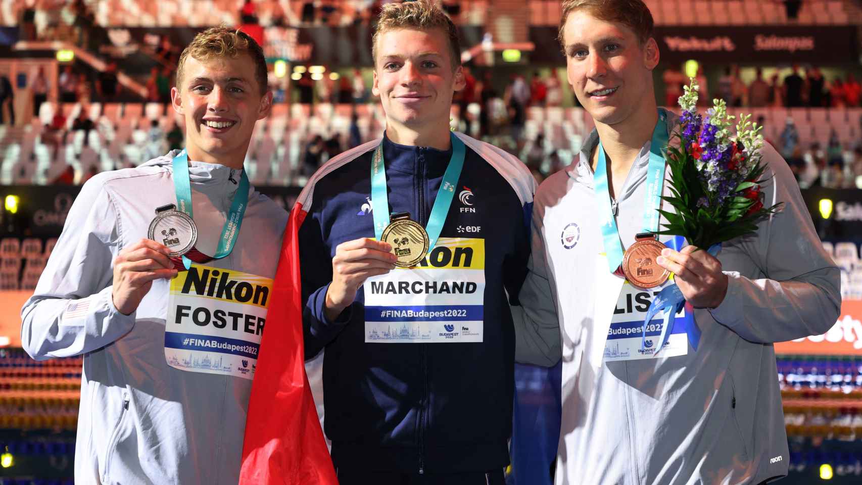 Leon Marchand, en el centro de la imagen, posa con su oro en los Mundiales de Budapest.