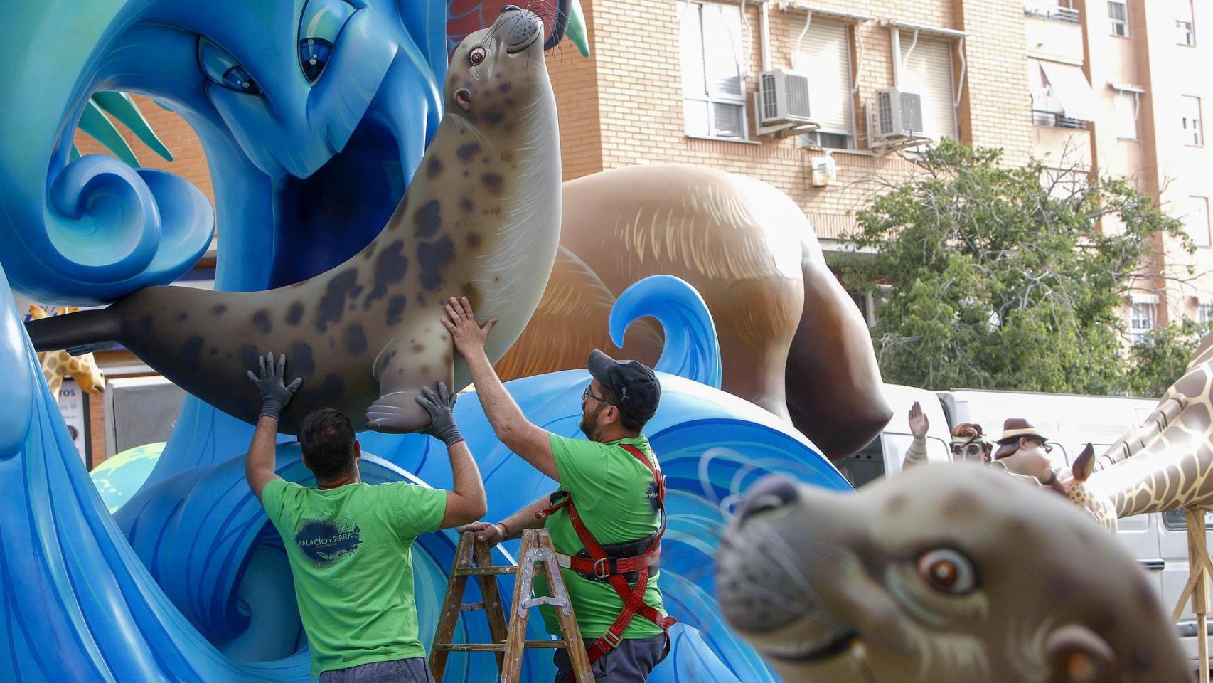 Operarios colocando un de los ninots en un monumento.