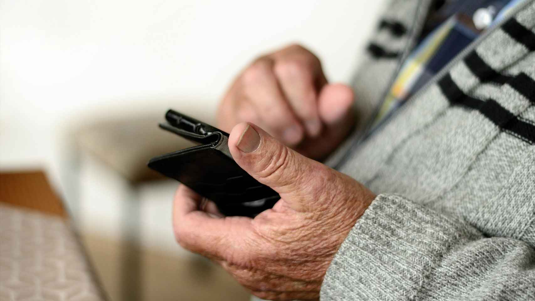 Una persona mayor usando su smartphone.