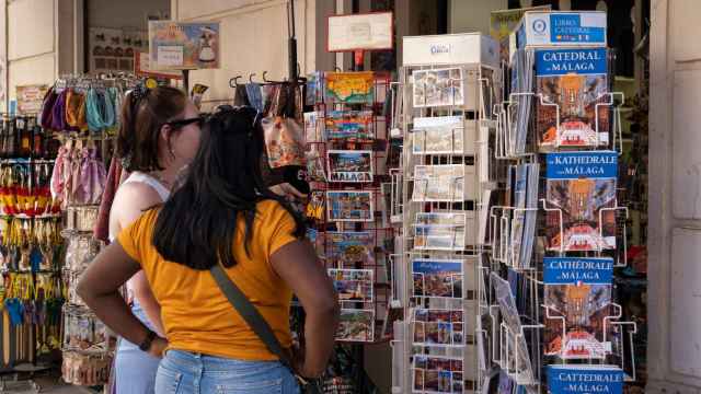 Unas turistas miran unas postales en Málaga.