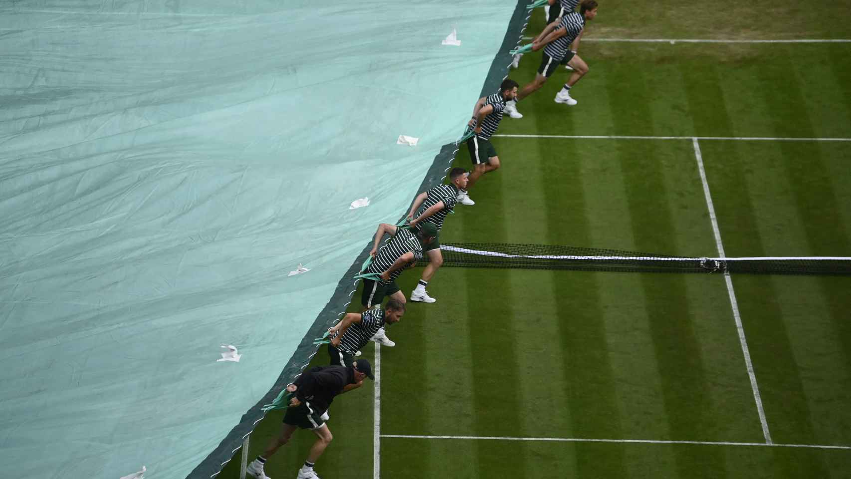 Operarios de Wimbledon cubren la pista de la central del All England Club de Wimbledon