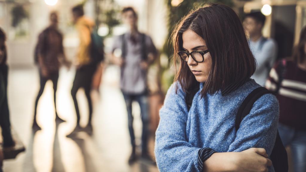 Una joven de secundaria sola y triste en un pasillo.