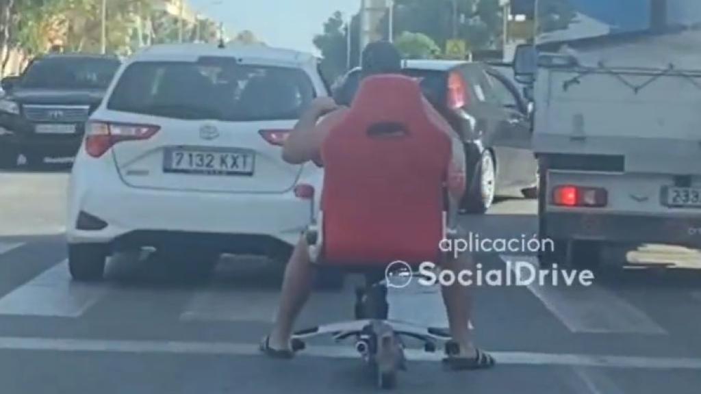 Un hombre circula con un patinete en una silla.