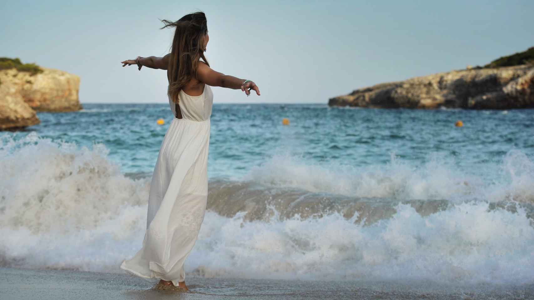 Una mujer pasea en una cala de Ibiza.