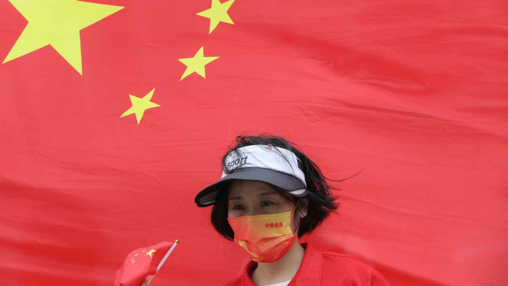 Una mujer pasa frente a una bandera china durante la celebración del 25 aniversario.