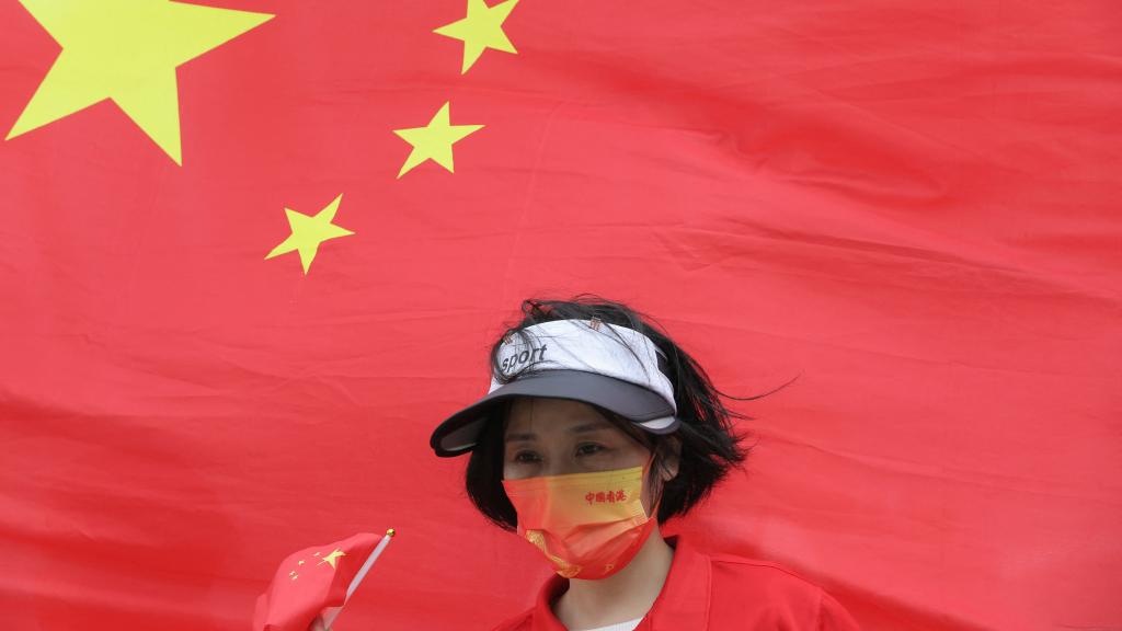 Una mujer pasa frente a una bandera china durante la celebración del 25 aniversario.