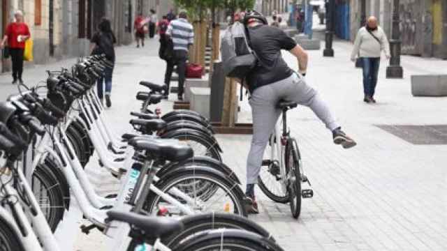 Un joven coge una bicicleta del servicio de BiciMAD del Ayuntamiento de Madrid.