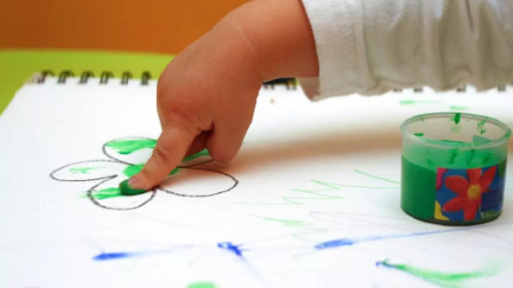 Un niño pintando con las manos.