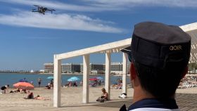Un agente de la Policía Local de Alicante observa el vuelo de un dron en una playa.