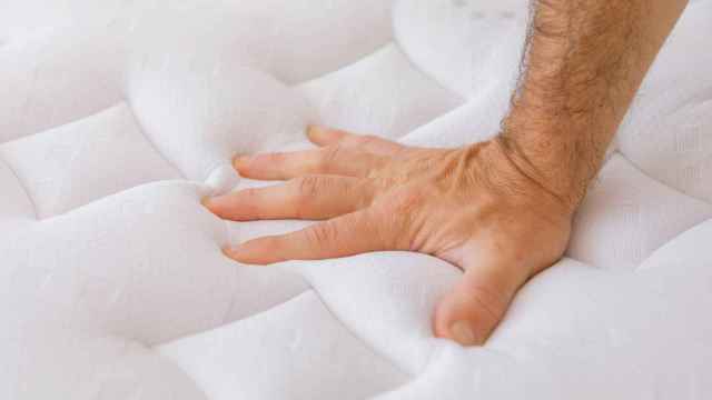 Una persona poniendo la mano en un colchón.