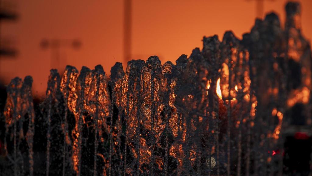 El sol se oculta tras una fuente en Zaragoza, este lunes.