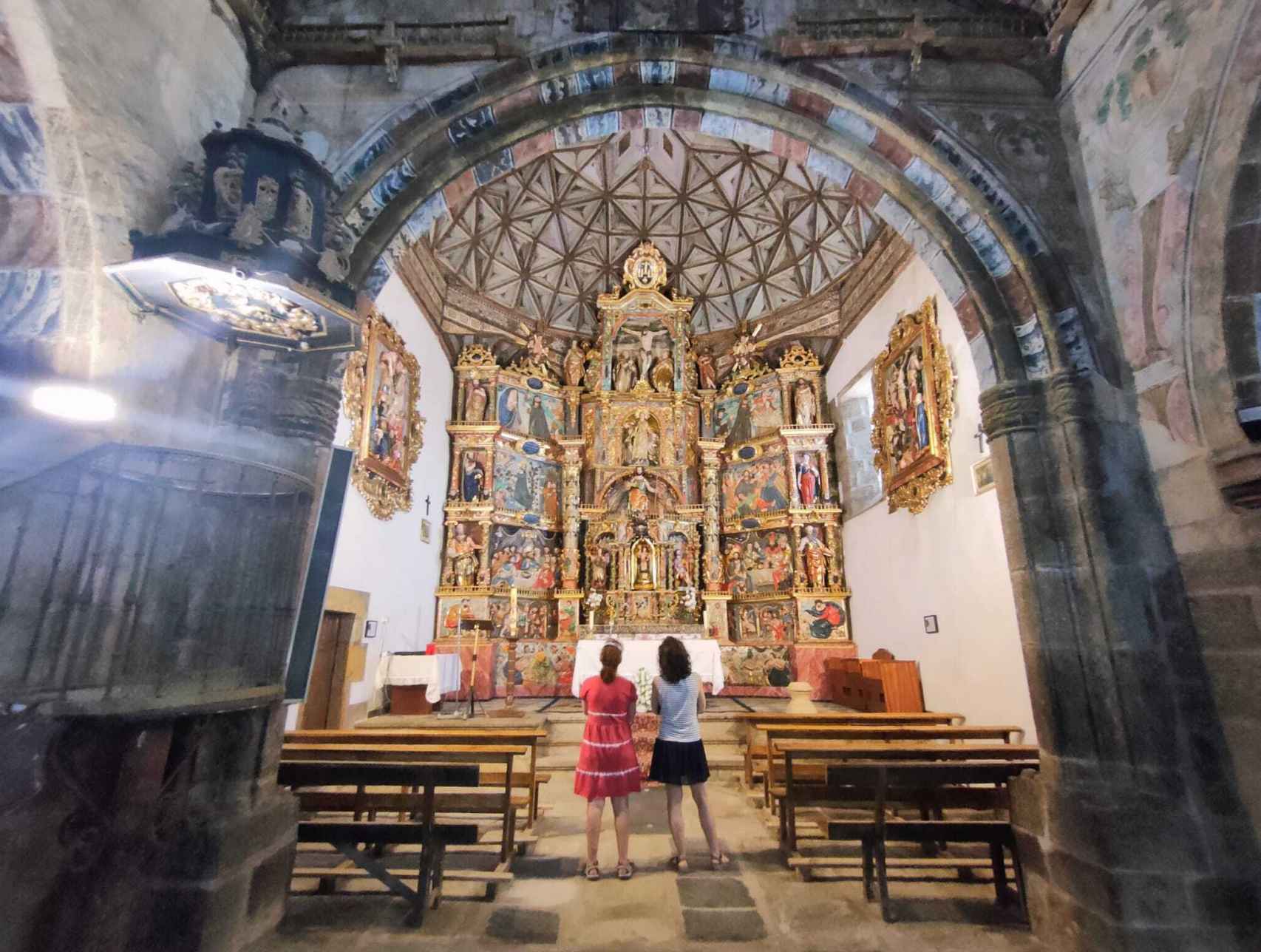 Dos turistas frente al retablo renacentista de la iglesia Santo Tomás Apóstol.