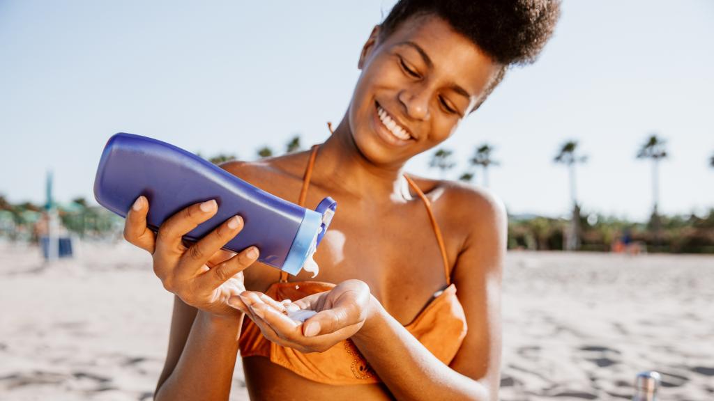 Mujer aplicándose protector solar en la playa