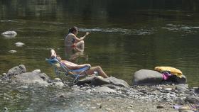 Dos personas se remojan en la orilla del río Miño, a 12 de julio de 2022, en Ourense.