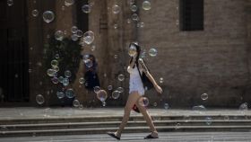 Una joven pasea entre pompas de jabón en Valencia.