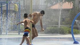 Dos personas se refrescan en unos chorros durante un día de calor en Ourense.