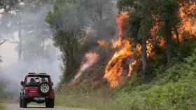 Un coche pasa cerca de las llamas en un incendio en Samos (Lugo).