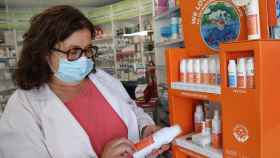 La palentina Carmen Calvo observa una crema solar en su farmacia
