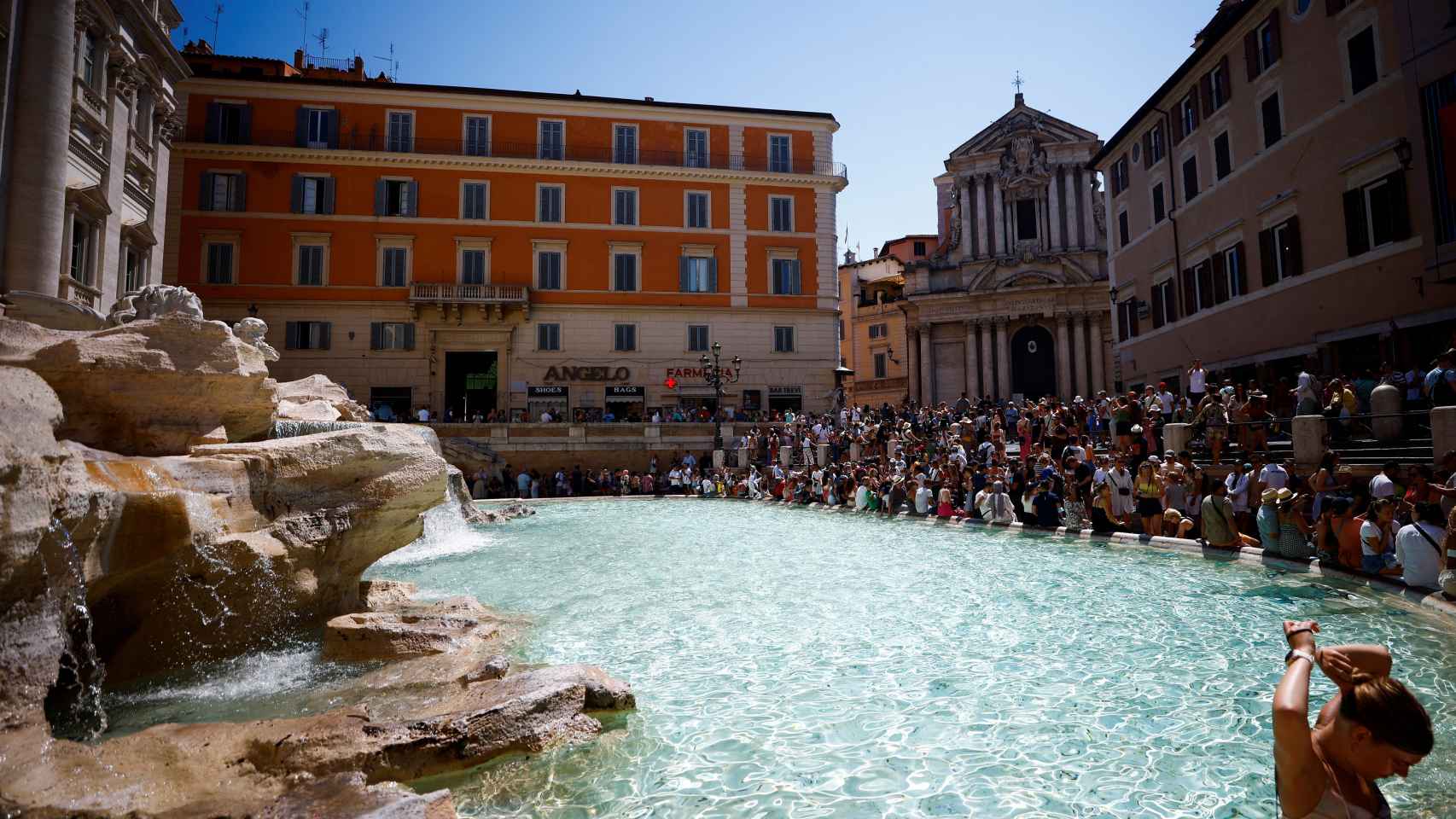 Turistas sentados en la Fontana de Trevi para sobrellevar el calor.