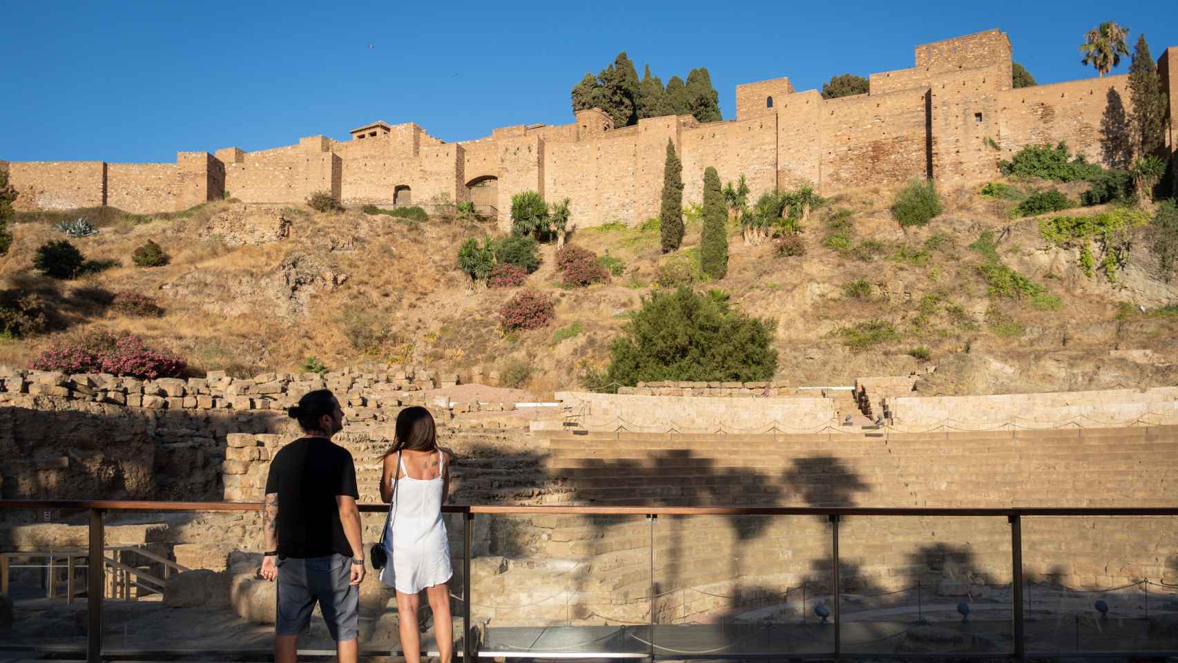 Una pareja de turistas mira hacia la Alcazaba de Málaga.