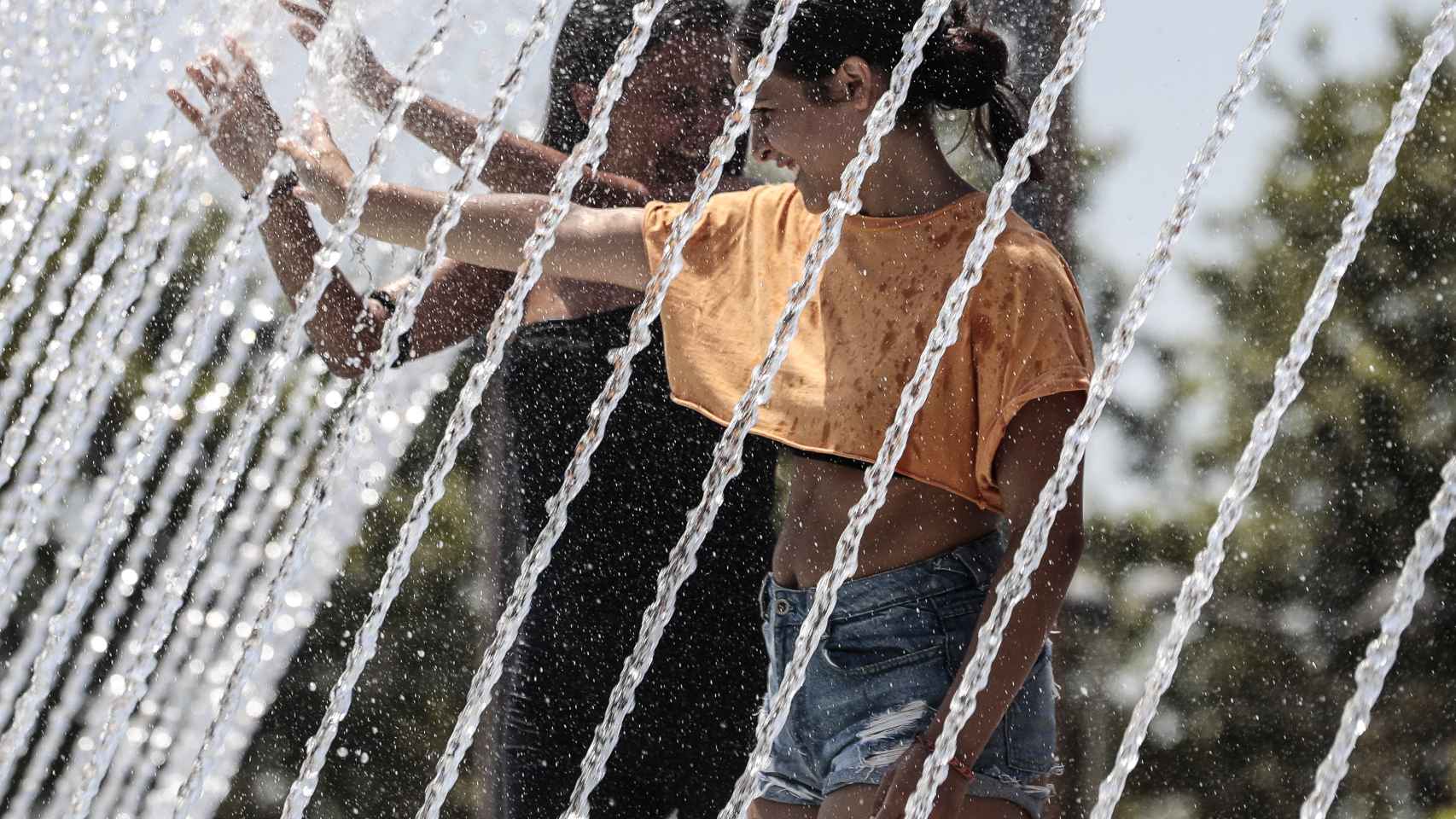 Dos chicas se refrescan ante las altas temperaturas de estos días, que ya hacen el verano más caluroso de la última década.