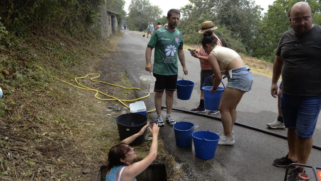 Vecinos preparan cubos de agua para trabajar en la extinción del incendio en O Barco.