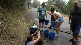 Vecinos preparan cubos de agua para trabajar en la extinción del incendio en O Barco.