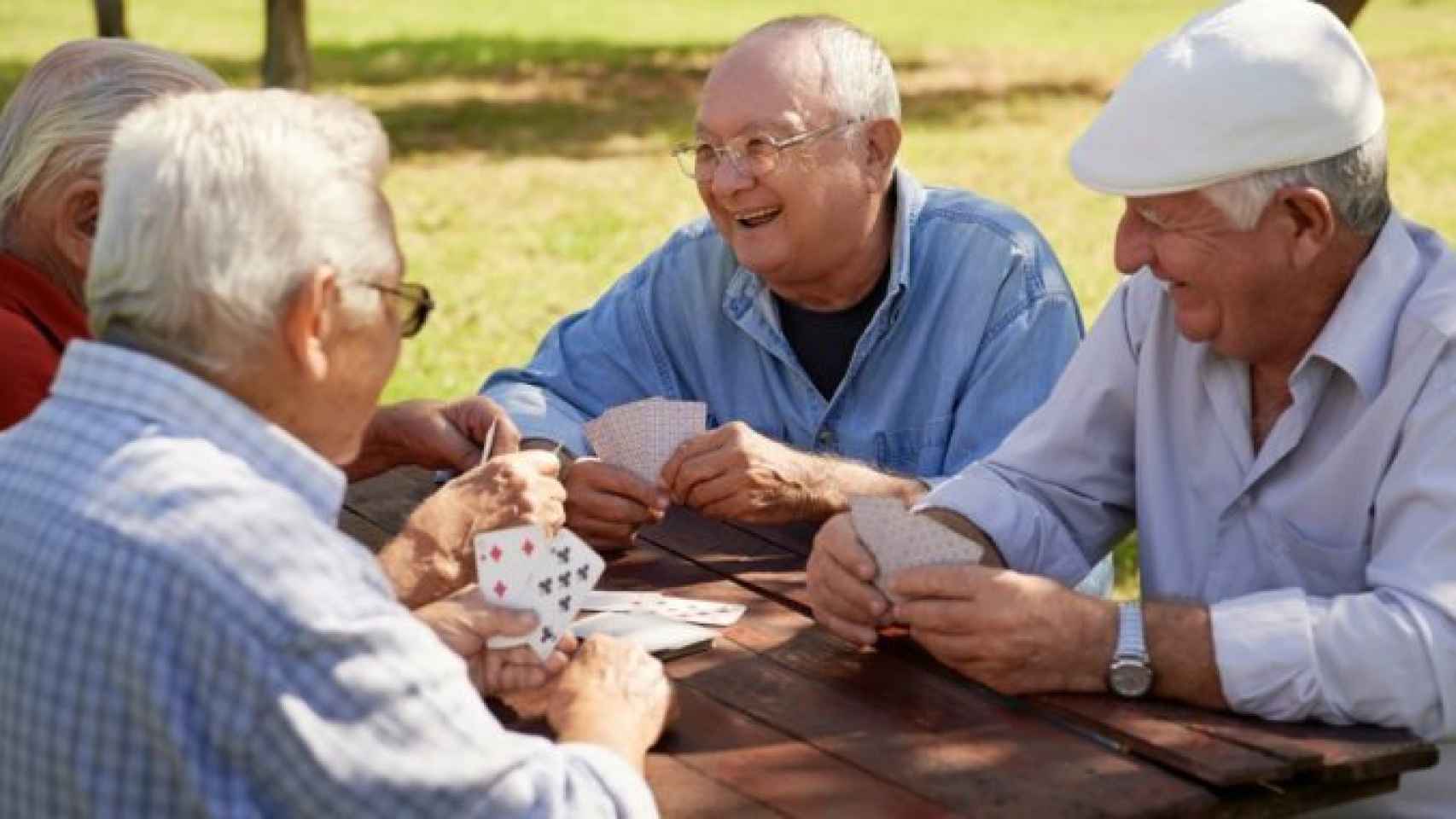 Un grupo de ancianos juega a las cartas en el parque.