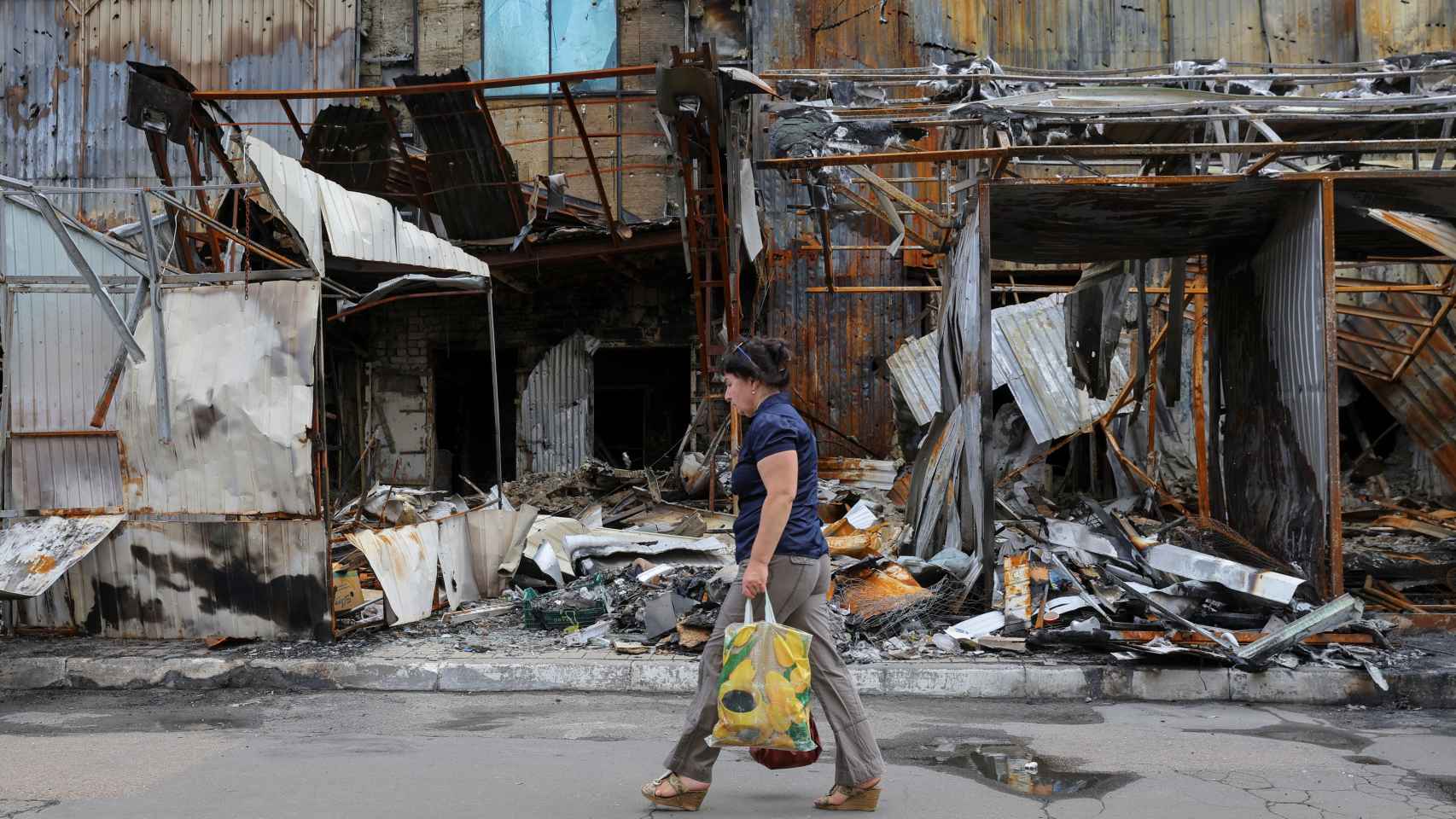 Una mujer pasa por delante de un mercado destruido por los ataques rusos en Donetsk