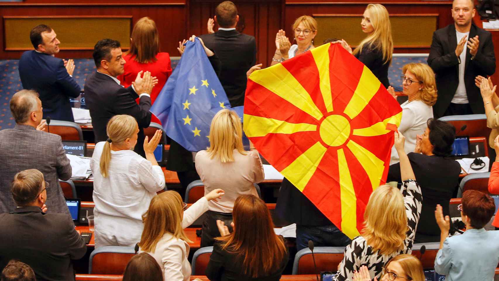 Miembros del partido gubernamental SDSM muestran banderas macedonias y de la UE en el Parlamento de Macedonia del Norte.