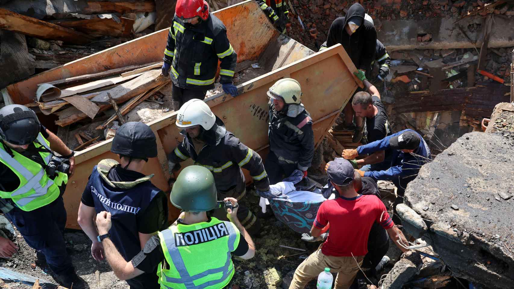 Operarios trabajando para retirar el cadáver de una mujer ucraniana entre los escombros en Járkov.