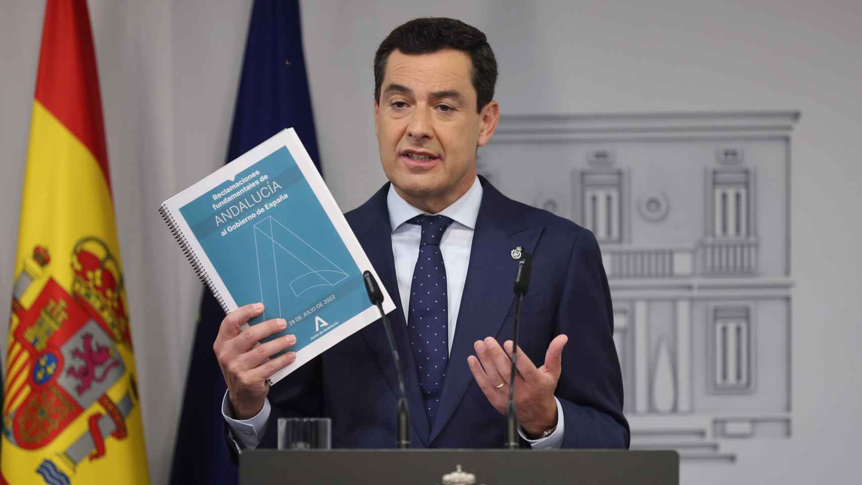 El presidente del Gobierno andaluz, Juanma Moreno, enseña en rueda de prensa el documento con las reivindicaciones que presentó a Pedro Sánchez.