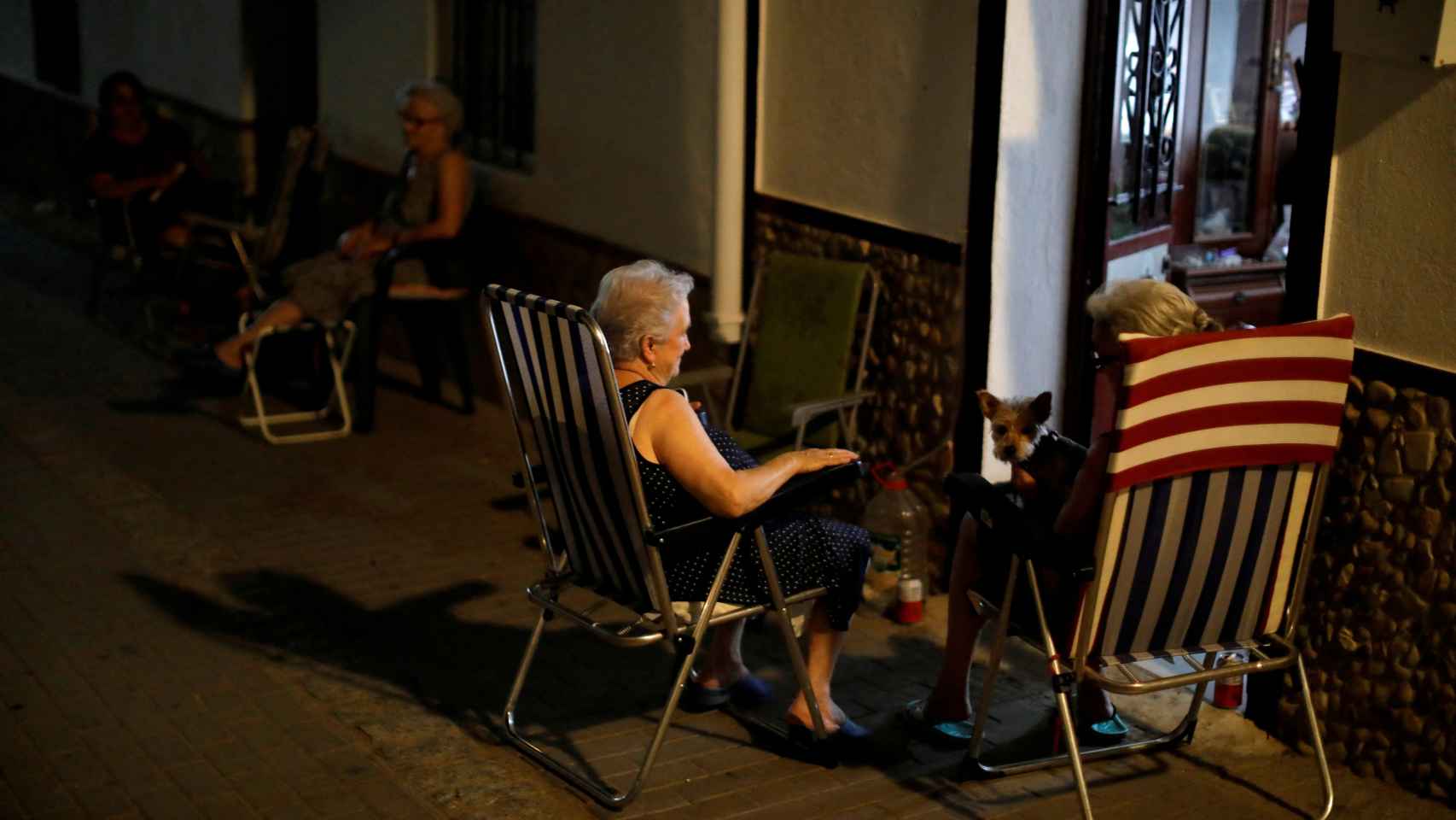 Tres mujeres toman el aire para evitar el calor dentro de sus casas, en Cádiz.