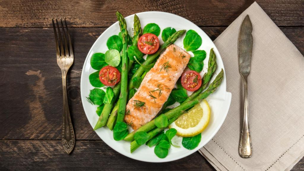 Imagen de archivo de una cena de salmón a la parrilla con espárragos y ensalada verde.