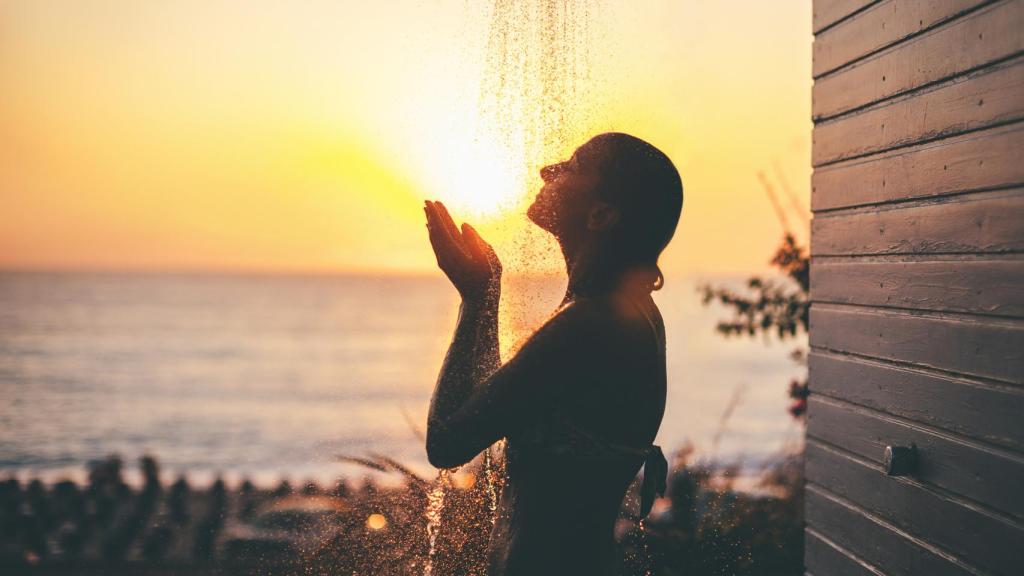 Una mujer duchándose al atardecer.