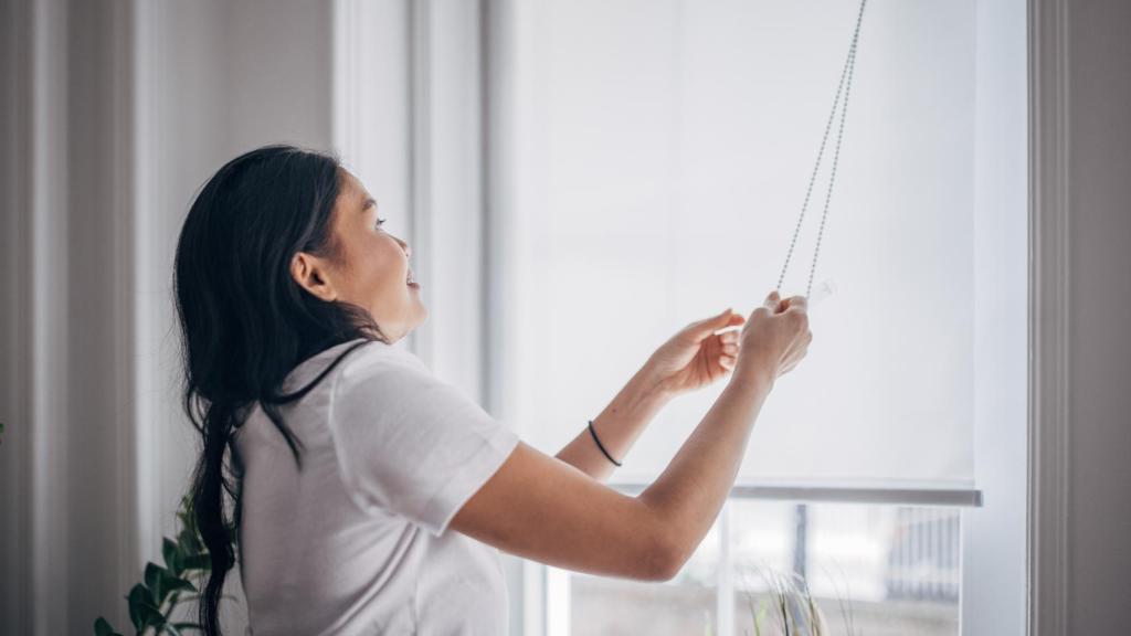 Mujer bajando las persianas.