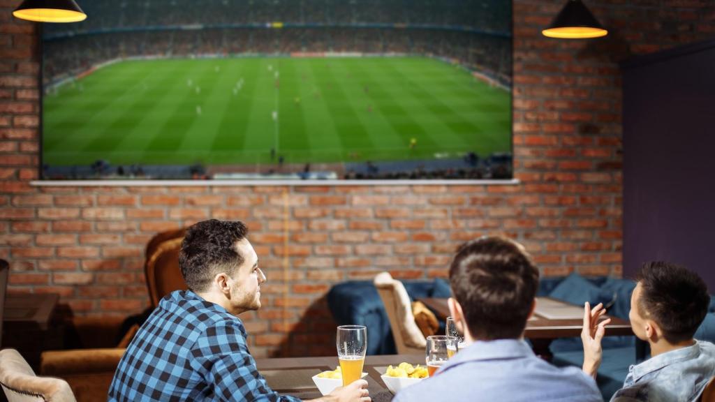 Aficionados viendo un partido de fútbol en bar.