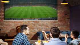 Aficionados viendo un partido de fútbol en bar.