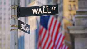 Cartel de Wall Street frente a una bandera de Estados Unidos.