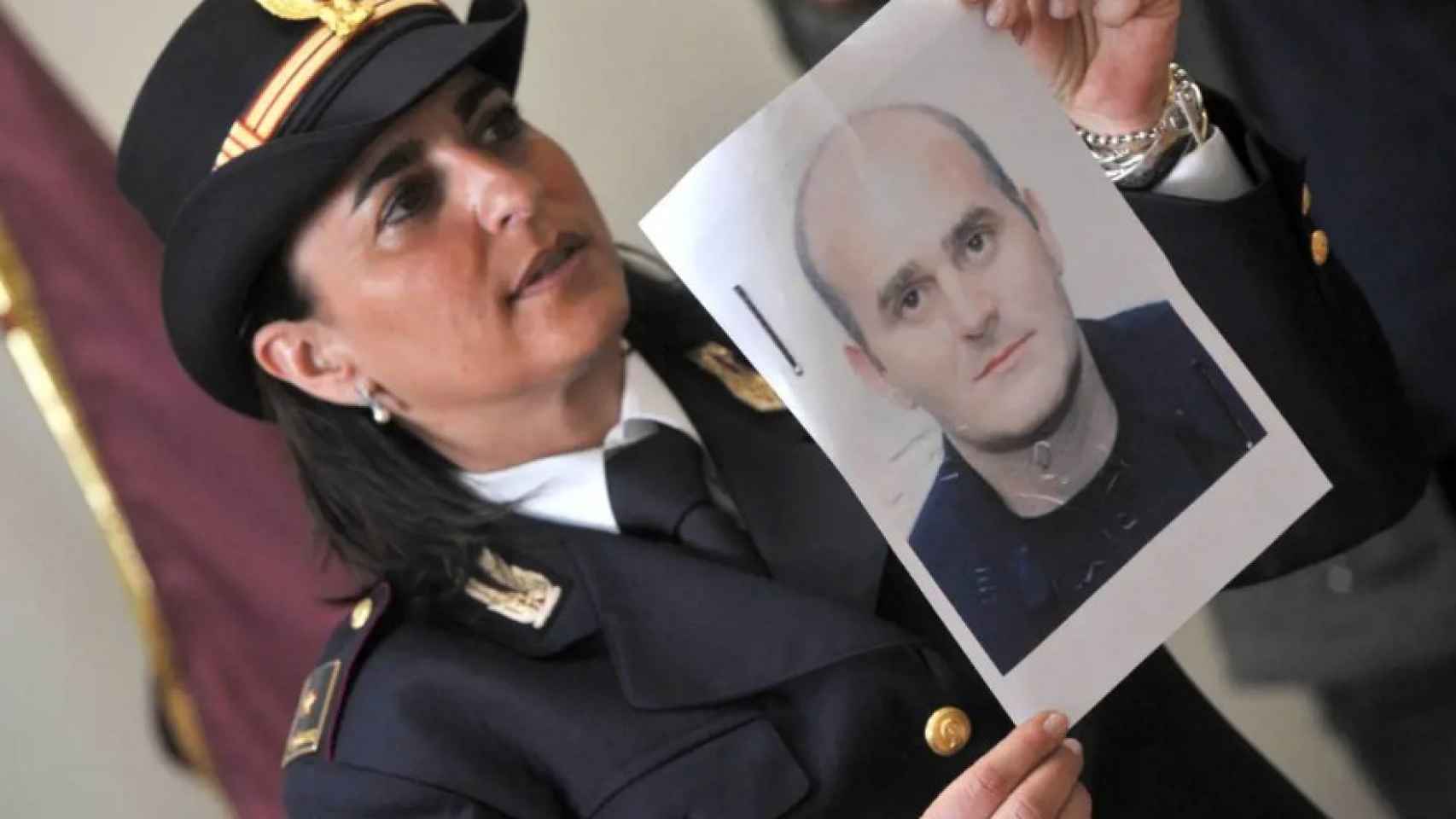 Una agente italiana mostrando la cara de Raffaele Amato tras su detención.