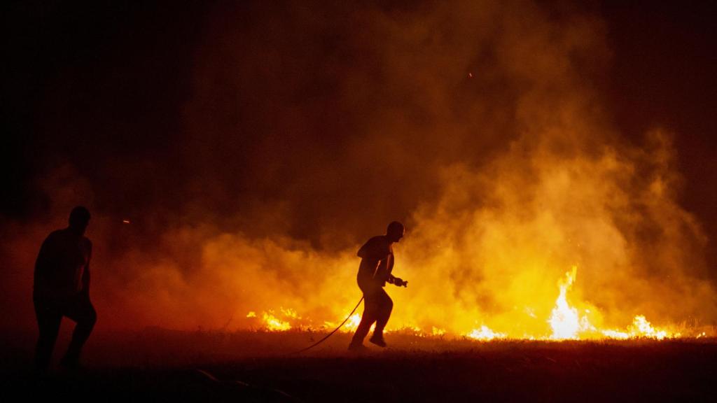 Dos vecinos colaboran en las labores de extinción del incendio de Cures, en Boiro, A Coruña.