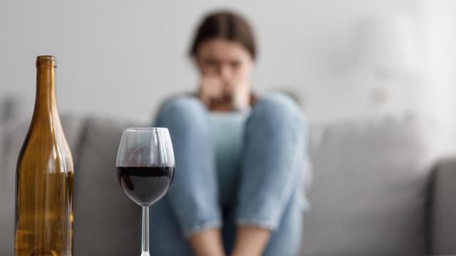 Una mujer frente a una copa de vino.