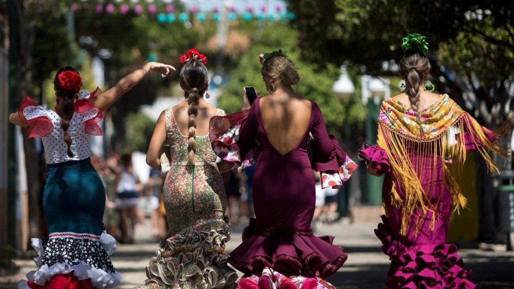 Tres personas vestidas de flamenca en la Feria de Málaga.