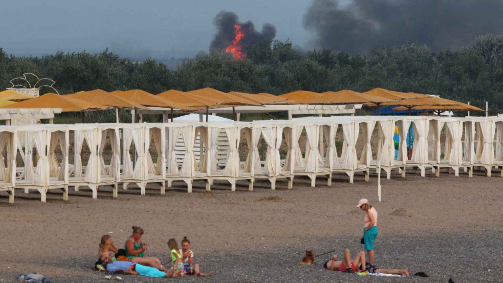 El humo de las explosiones en un aeródromo militar en Crimea desde una playa cercana.