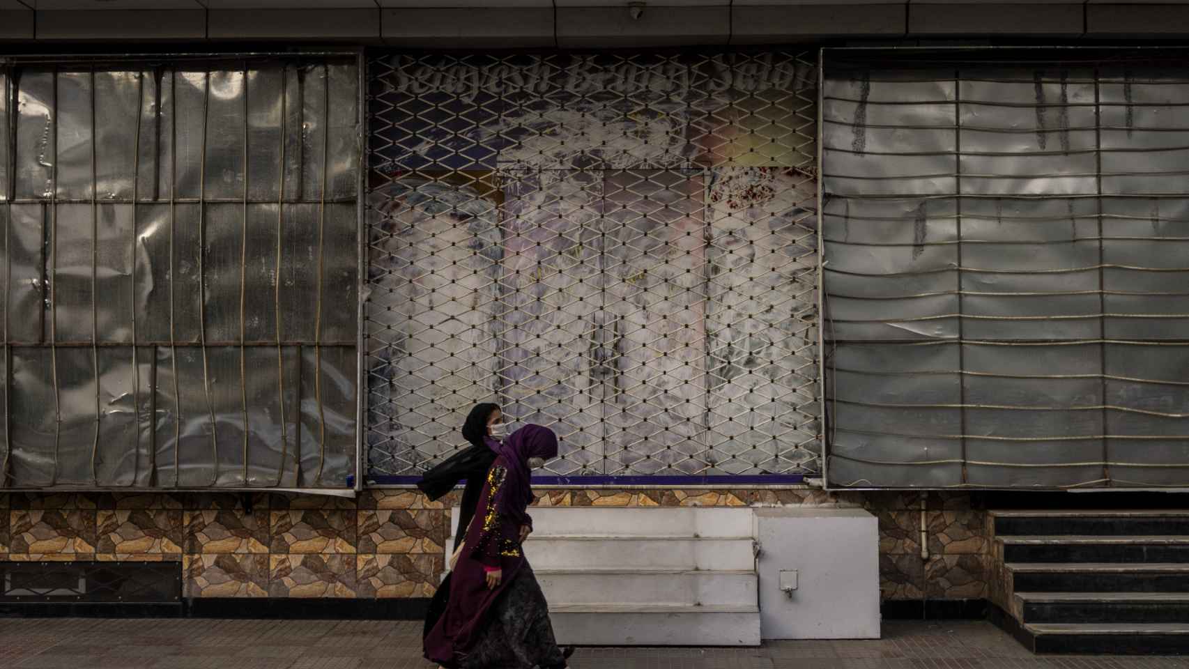 Mujeres afganas pasan por delante de un comercio cerrado en octubre de 2021